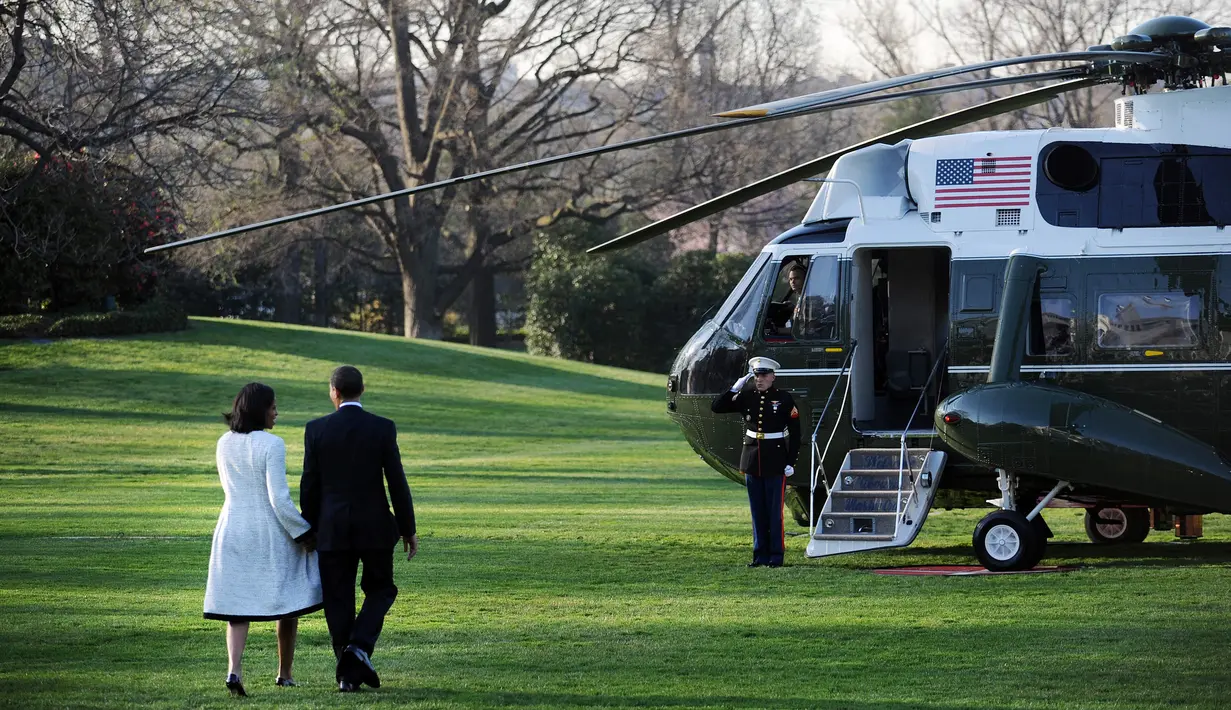 Presiden Amerika Serikat (AS) ke-44, Barack Obama menggandeng tangan sang istri, Michelle Obama, saat berjalan menuju helikopter kepresidenan Marine One untuk memulai perjalanan ke Eropa, di Gedung Putih, Washington, 31 Maret 2009. (AFP PHOTO / TIM SLOAN)