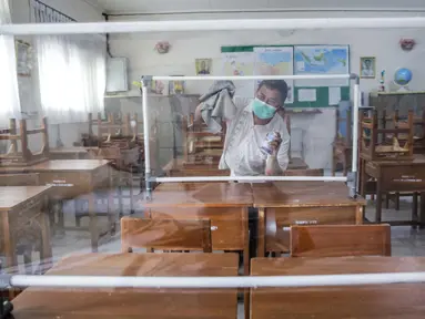 Petugas menyiapkan ruangan kelas yang akan digunakan di SMP N 115 Jakarta, Jumat (21/5/2021). Seleksi PPDB DKI Jakarta tahun ini akan dibagi menjadi empat bagian yakni jalur prestasi, jalur afirmasi, jalur zonasi, dan jalur pindah tugas orangtua dan anak guru. (Liputan6.com/Faizal Fanani)