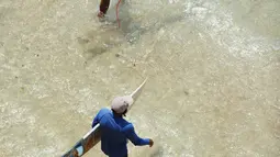 Dua wisatawan bersiap untuk bermain selancar di pantai Uluwatu Kuta Selatan di Kabupaten Badung, Bali pada 20 Desember 2018. Jutaan turis mancanegara datang ke Bali untuk berburu spot berselancar paling menantang. (Photo by SONNY TUMBELAKA / AFP)