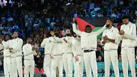 Atlet basket Prancis Mathias Lessort (membentangkan bendera Martinik) bergabung bersama rekan setimnya di podium menunggu pengalungan medali perak dari cabang basket putra. (dok. Damien MEYER / AFP)