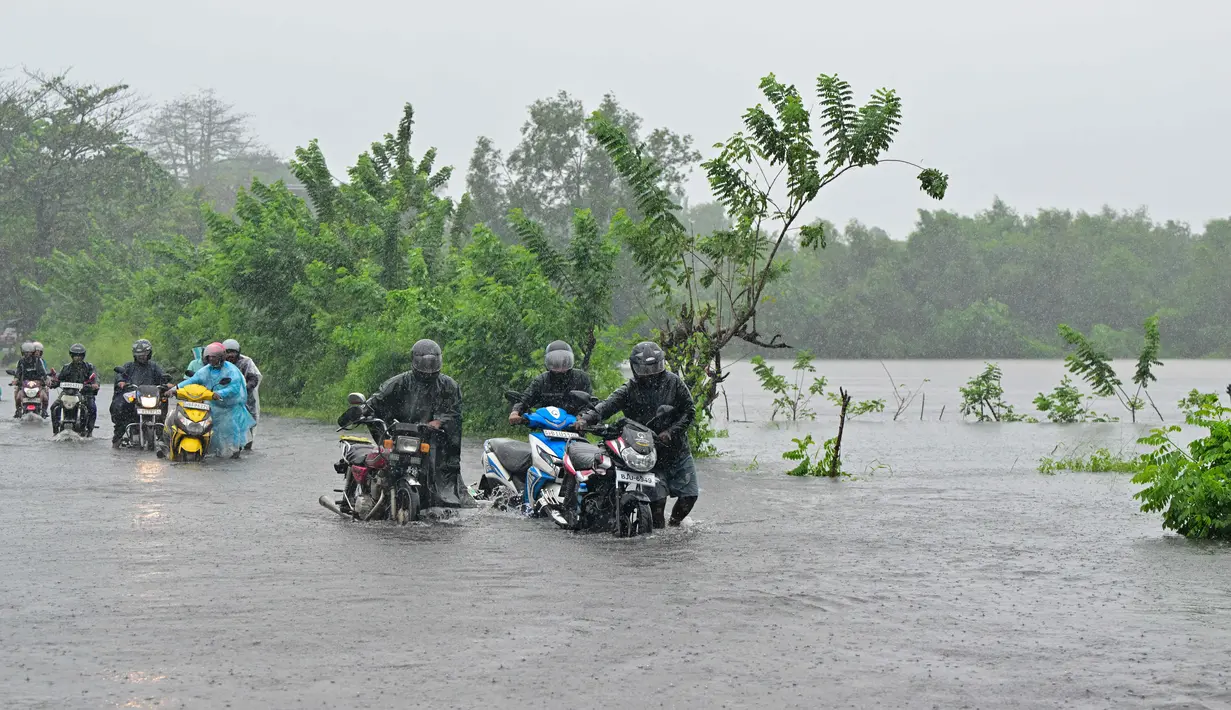 Departemen Meteorologi memperingatkan badai tersebut dapat menguat saat bergerak melintasi pulau itu dalam 12 jam ke depan. Tampak dalam foto, para pengendara berjalan di jalanan yang terendam banjir di Biyagama, pinggiran Kolombo, pada Jumat 28 November 2025. (Ishara S. KODIKARA/AFP)