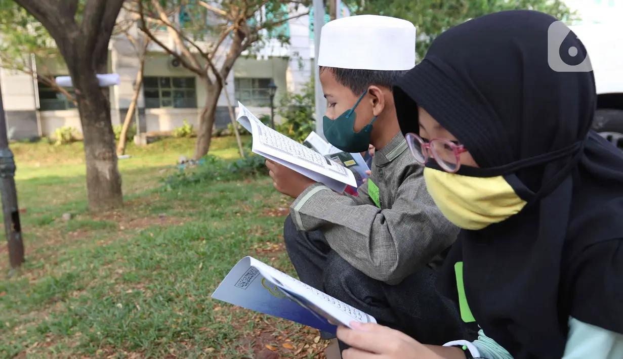 Anak-anak membaca Al-Quran sambil menunggu waktu berbuka puasa di halaman Masjid Raya Jakarta Islamic Center, Jakarta Utara, Senin (18/4/2022). Acara ngabuburit sambil khataman Al-Quran ini merupakan rangkaian acara menyambut 17 Ramadhan atau malam Nuzulul Quran. (Liputan6.com/Herman Zakharia)