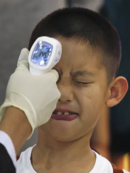 Seorang anak laki-laki mendapatkan pemeriksaan suhu badan oleh petugas tiba di Bandara Internasional Bangkok Suvarnabhumi, Thailand, Minggu (21/6/2015). WHO mencatat ada 1.334 kasus MERS di 26 negara. (REUTERS/Kerek Wongsa)