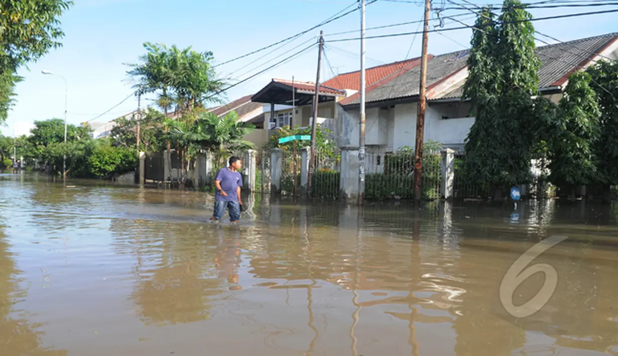 Hujan yang mengguyur Jakarta sejak Minggu (8/2) lalu, membuat Waduk Ria Rio meluap. Seorang warga tampak melintasi jalan yang tergenang banjir di kawasan Perumahan Pulomas, Jakarta, Selasa (10/2/2015). (Liputan6.com/Herman Zakharia)