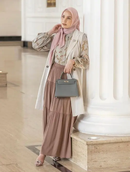 Kali ini, Dwi bermain dengan motif lewat paduan kemeja floral warga sage green yang dipadukan dengan sleeveless outer warna beige dan tiered skirt warna coklat. Sementara untuk hijab, Dwi memilih warna soft pink. (Instagram/dwihandaanda).