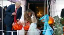 Presiden AS, Donald Trump dan Ibu Negara, Melania Trump membagikan permen kepada anak-anak saat open house perayaan pesta Halloween di Gedung Putih, Senin (30/10). Para siswa dan orang tua dari 20 sekolah hadir di acara ini. (AP/Pablo Martinez Monsivais)