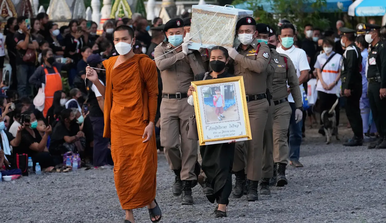 Polisi membawa peti mati berisi korban serangan pusat penitipan anak untuk dikremasi di Kuil Wat Rat Samakee, Uthai Sawan, Thailand, Selasa (11/10/2022). Untuk melakukan proses kremasi, tungku darurat yang terbuat dari batu bata tanah liat dibangun di kuil-kuil Buddha di sebuah kota di timur laut Thailand. (AP Photo/Sakchai Lalit)