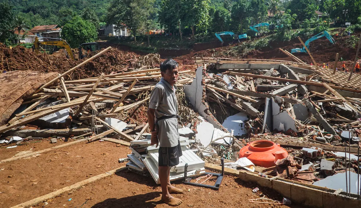 Pemerintah Kabupaten Cilacap dan tim SAR gabungan terus berupaya maksimal dalam operasi pencarian dan penanganan pasca-bencana. Tampak dalam foto, seorang pria setempat menyaksikan para tim penyelamat mencari korban setelah longsor menimbun beberapa rumah di Desa Cibeunying, Kabupaten Cilacap, Jawa Tengah, pada Senin 17 November 2025. (Bakhtiar RAHMAN/AFP)