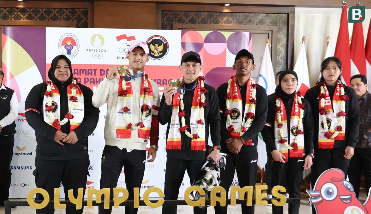 <p>Dua atlet Indonesia peraih medali emas di Olimpiade 2024 Paris: Rizki Juniansyah dan Veddriq Leonardo (tengah) bersama rombongan terakhir atlet Indonesia yang berjuang di Olimpiade 2024 usai&nbsp;tiba di Bandara Internasional Soekarno-Hatta, Tangerang, Selasa (13/8/2024). (Abdul Aziz/Bola.com).</p>
