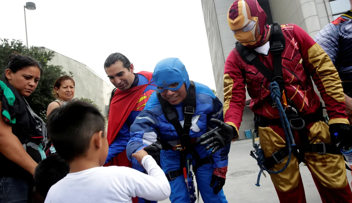 Petugas pembersih kaca berkostum superhero menyapa seorang anak di luar rumah sakit anak-anak di Guadalupe, Meksiko, 30 April 2019. Mereka bergelantungan di luar jendela dengan mengenakan kostum superhero untuk menghibur anak- anak yang sedang sakit. (REUTERS/Daniel Becerril)