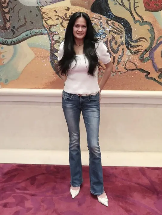 Donna Harun tampak masih muda dengan mengenakan atas putih dengan lengan ballon yang dikombinasikan dengan celana denim dan heels slopnya serasi dengan warna atasannya. Rambut panjang hitamnya pun dibiarkan terurai (@donnaharunofficial)