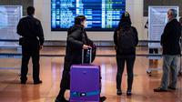 Penumpang berjalan melalui aula kedatangan di Bandara Internasional Haneda Tokyo, Jumat (18/2/2022). Pemerintah Jepang mengumumkan rencana untuk melonggarkan aturan perbatasan virus bagi pekerja dan pelajar. (AFP/Philip Fong)