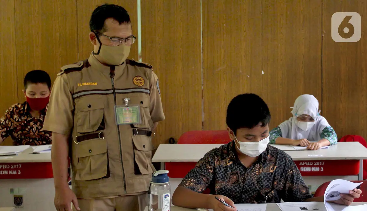 Guru mengawasi murid saat kegiatan Kompetisi Sains Nasional (KSN) seleksi Tingkat SD/ MI se-Kota Depok mata pelajaran IPA di SDN Kemirimuka 3, Depok, jawa Barat, Senin (22/3/2021). Pelaksanaan KSN diikuti perwakilan murid  dari 11 kecamatan di wilayah Depok. (merdeka.com/Arie Basuki)