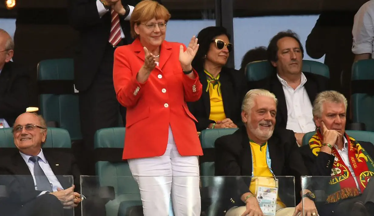 Kanselir Jerman, Angela Merkel (tengah) berdiri memuji permainan Philipp Lahm dkk saat berlaga di babak penyisihan Piala Dunia 2014 Grup G di Fonte Nova Arena, Brasil, (16/6/2014). (AFP PHOTO/Fabrice Coffrini)
