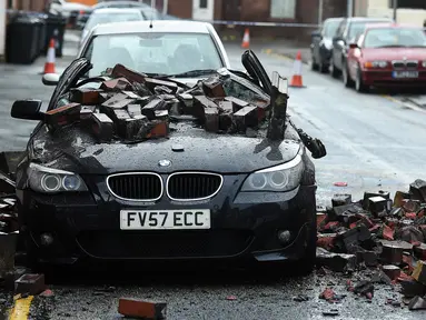 Sebuah mobil yang diparkir rusak terkena batu karena angin kencang yang disebabkan oleh atap apartemen yang runtuh di Leigh, barat laut Inggris, Rabu (18/11). (AFP PHOTO/Paul Ellis)