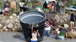 Sejumlah Warga Kolombia membawa barang-barang mereka saat melintasi sungai Tachira, Venezuela, (25/8/2015). Sebanyak 1.012 warga Kolombia dideportasi dari Venezuela. (REUTERS/Jose Miguel Gomez)