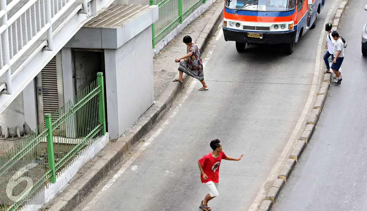 Pejalan kaki menyeberang di bawah Jembatan Penyeberangan Orang (JPO) di Jakarta, Kamis (19/11). Selain membahayakan keselamatan, perilaku buruk pejalan kaki tersebut juga menjadi salah satu penyebab kemacetan di Ibu Kota. (Liputan6.com/Immanuel Antonius)