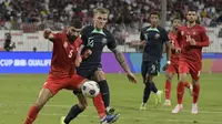 Bek Timnas Bahrain, Hamad Al-Shamsan, berebut bola dengan gelandang Timnas Australia, Riley McGree, dalam laga Kualifikasi Piala Dunia 2026 zona Asia di Bahrain National Stadium, Riffa, Rabu (20/11/2024) dini hari WIB. (Mazen Mahdi / AFP)