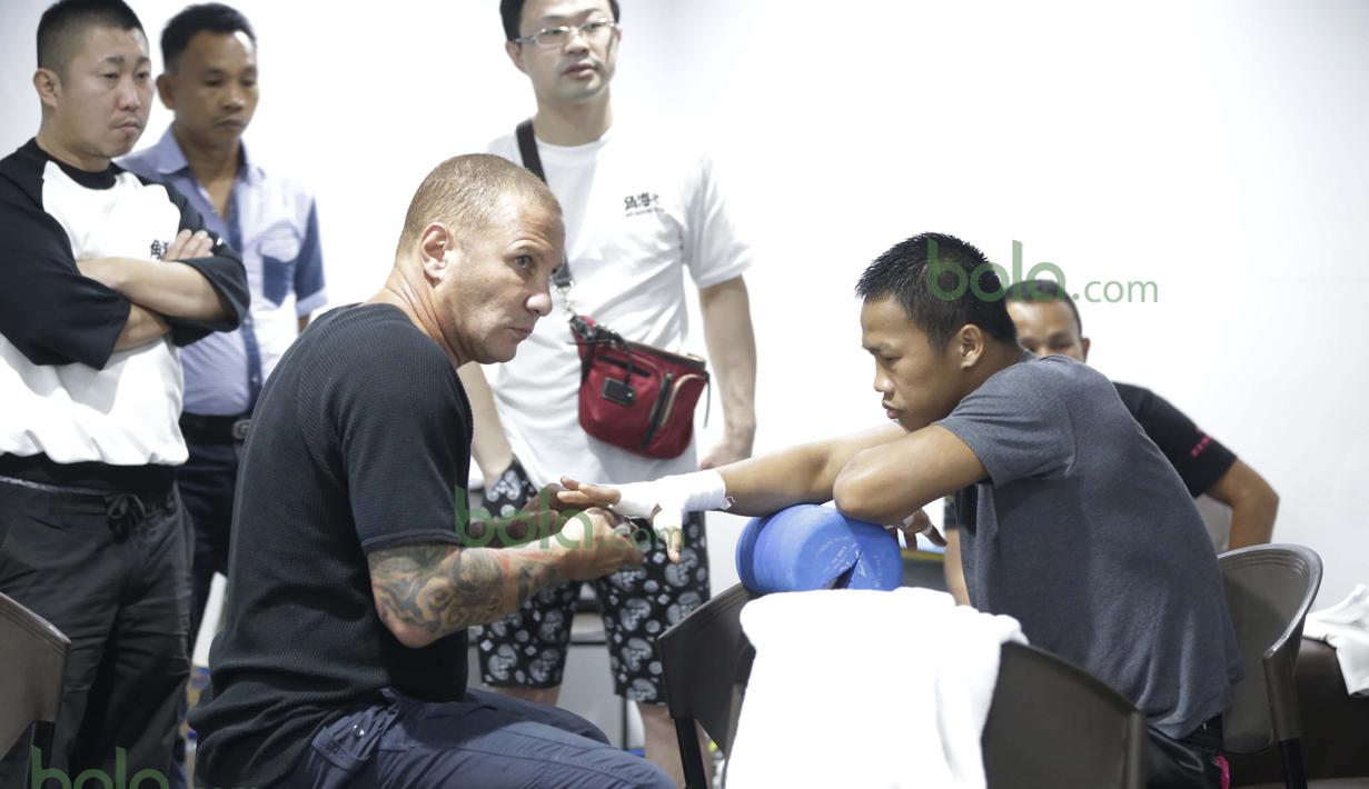 Pelatih Craig Christian sedang memasang perban pada tangan Daud Yordan diruang ganti sebelum bertanding melawan Yoshitaka Kato di Balai Sarbini, Jakarta, Jumat (5/2/2016). (Bola.com/Nicklas Hanoatubun)