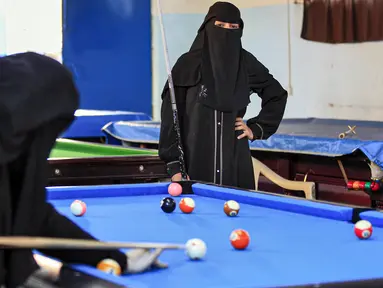 Seorang wanita melihat lawannya membidik bola saat mengikuti kejuaraan biliar lokal di sebuah gedung olahraga di ibu kota  Sanaa, Yaman  (16/12/2019).  (AFP/Mohammed Huwais)