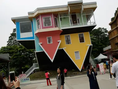 Pengunjung berpose di depan rumah terbalik di Huashan Creative Park, Taipei, Taiwan, (7/4). Sekelompok arsitek Taiwan membangun rumah seluas 300 meter yang menghabiskan dana US$ 600.000 dalam kurun waktu 2 bulan. (REUTERS/Tyrone Siu)