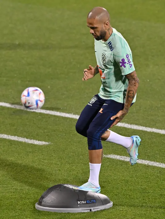 Bek Brasil, Dani Alves mengambil bagian dalam sesi latihan di Stadion Al Arabi SC di Doha (6/12/2022). Brasil melaju ke perempatfinal Piala Dunia 2022 setelah mengalahkan Korea Selatan dengan skor 4-1. (AFP/Nelson Almedia)