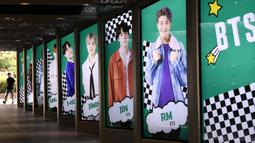 Warga melewati poster komersial anggota boyband K-pop, BTS, di luar toko bebas pajak di Seoul, Selasa (1/9/2020). Lagu "Dynamite" puncaki tangga lagu Billboard dan membuat BTS menjadi penyanyi Kpop sekaligus grup Asia pertama yang meraih posisi nomor satu di Billboard Hot 100. (Jung Yeon-je/AFP)