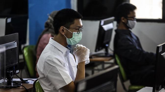 Peserta mengenakan masker dan sarung tangan saat mengikuti Seleksi Bersama Masuk Perguruan Tinggi Negeri (SBMPTN) di Universitan Negeri Jakarta, Minggu (5/7/2020). Sebanyak 42.463 peserta mengikuti SBMPTN dengan prosedur protokol kesehatan. (Liputan6.com/Faizal Fanani)