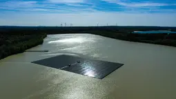 Pemandangan dari udara menunjukkan panel surya dengan turbin angin di kejauhan di pabrik fotovoltaik terapung di danau Silbersee di Haltern, Jerman barat (22/4/2022). Taman surya terapung terbesar di Jerman saat ini sedang dibangun. (AFP/Ina Fassbender)