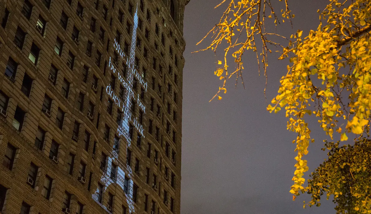 Sebuah proyeksi Menara Eiffel ditampilkan di sisi bangunan Flatiron New York City, Rabu (18/11). Gambar yang menampilkan tulisan She is tossed by waves but does not sink itu bentuk solidaritas terkait serangan teror Paris. (Andrew Burton/Getty Images/AFP)