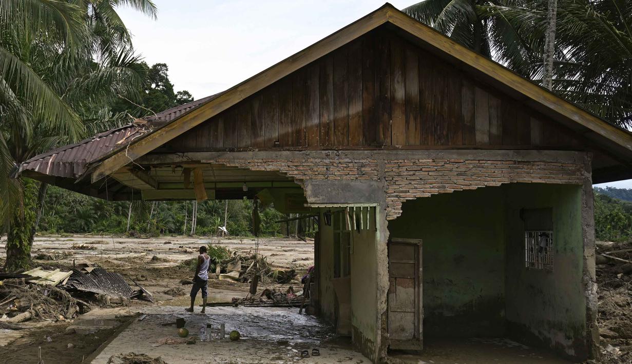 Seorang warga desa melihat-lihat dari rumahnya yang rusak akibat banjir bandang di Garoga, Provinsi Sumatera Utara, pada Kamis 4 Desember 2025. (YT HARIONO/AFP)