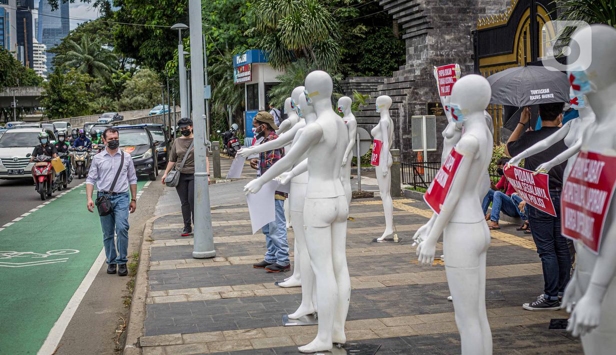 Kendaraan melintas di depan manekin yang dipajang dalam aksi di Polda Metro Jaya, Senin (21/3/2022). Aksi tersebut bentuk dukungan terhadap Haris Azhar dan Fatia Maulidiyanti saat menjalani pemeriksaan terkait kasus dugaan pencemaran nama baik Luhut Binsar Pandjaitan. (Liputan6.com/Faizal Fanani)