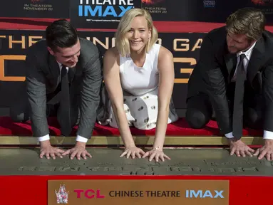 Pemain film " The Hunger Games : Mockingjay - Part 2" Josh Hutcherson, Jennifer Lawrence dan Liam Hemsworth (ki-ka) saat memberikan cap telapak tangan dan kaki di TCL Chinese theatre di Hollywood, California, Sabtu (31/10/2015). (REUTERS/Mario Anzuoni)