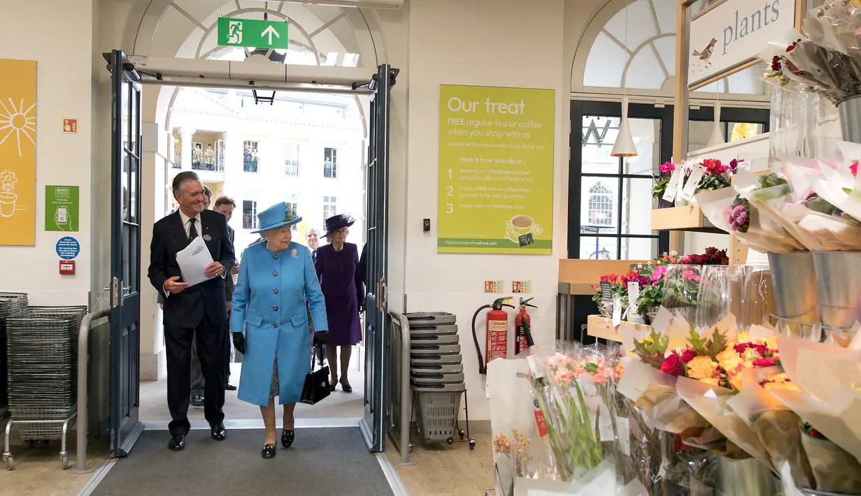 Ratu Inggris Elizabeth II bersama rombongan didampingi Direktur pasar swalayan Waitrose, Rupert Thomas saat tiba di pasar swalayan Waitrose pada kunjungannya di Kota Poundbury, Inggris (27/10). (Reuters/Justin Tallis)