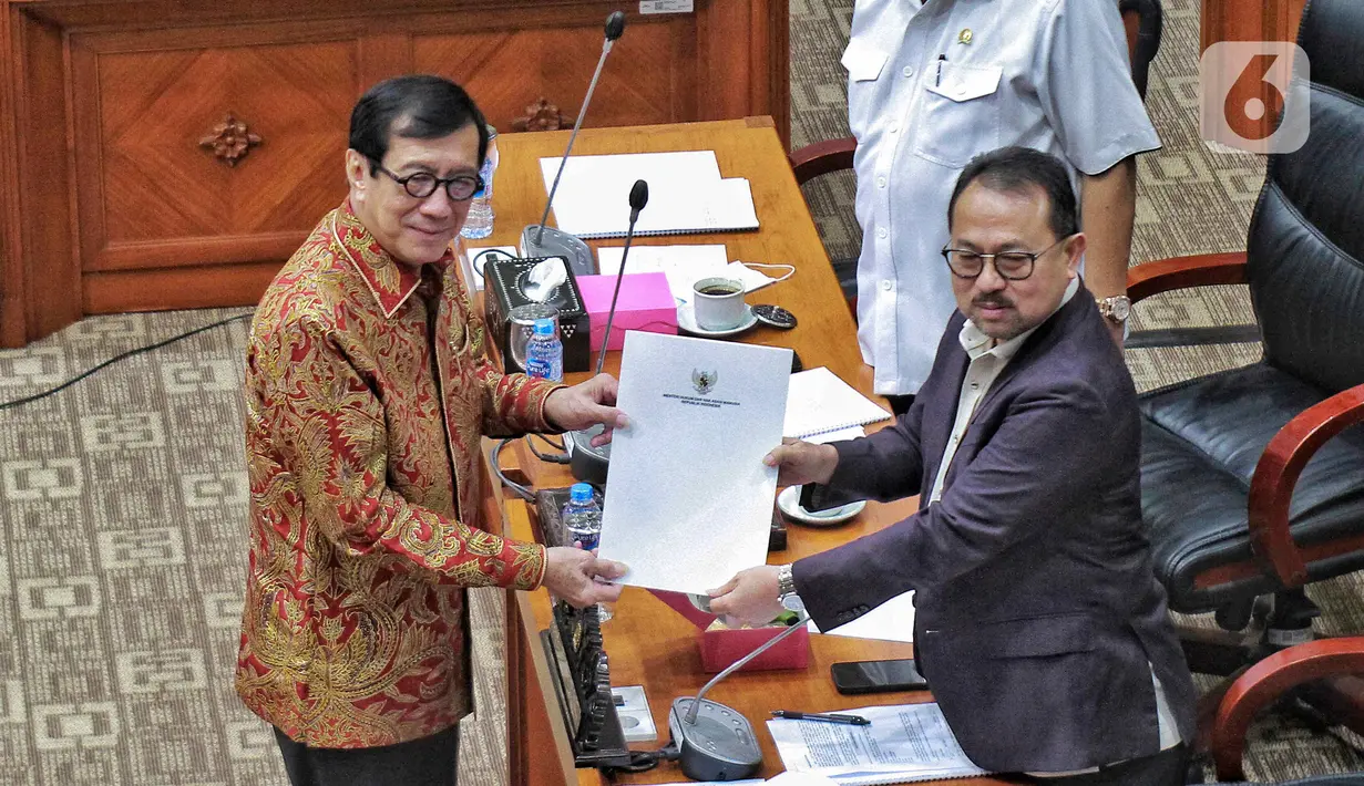 Menteri Hukum dan HAM RI Yasonna Laoly (kiri) menyerahkan RUU kepada Wakil Ketua Komisi III DPR RI Pangeran Khairul Saleh (kanan) saat Rapat Kerja dengan Komisi III DPR RI di gedung Parlemen, Jakarta, Senin (5/12/2022). Rapat kerja membahas RUU tentang pengesahan perjanjian antara Pemerintah Republik Indonesia dengan Pemerintah Republik Singapura tentang ekstradisi buronan. (Liputan6.com/Angga Yuniar)