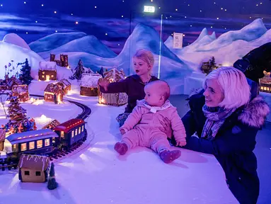 Seorang ibu dan anak-anaknya melihat pameran desa jahe di Bergen, Norwegia pada 18 November 2019. Pameran tahunan yang populer ini menampilkan ratusan rumah dan struktur lainnya dari kue jahe yang identik dengan perayaan Natal. (Marit Hommedal / NTB Scanpix / AFP)