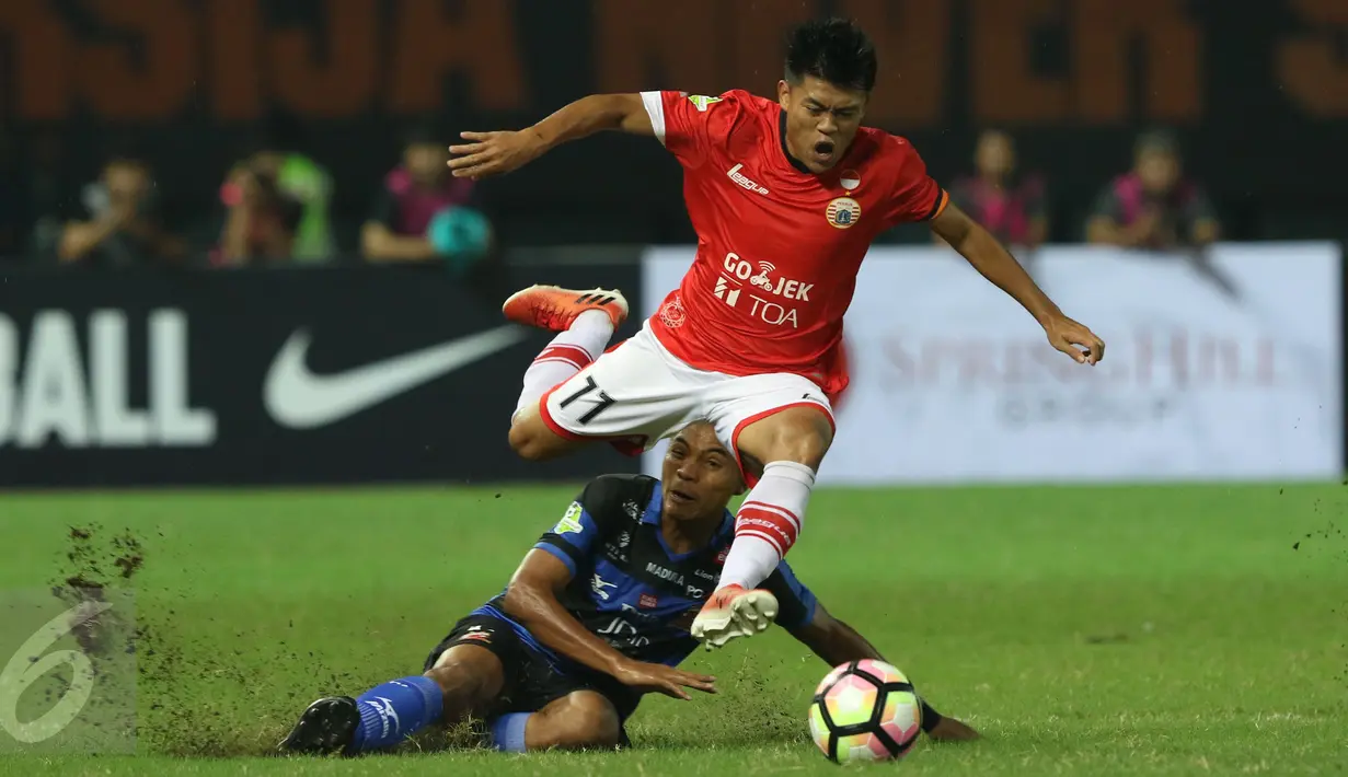 Gelandang Persija, Jepri Kurniawan (atas) melompat menghindari tekel bek Madura United, Asep Berlian saat laga lanjutan Liga 1 di Stadion Patriot Candrabhaga, Bekasi, Kamis (4/5). Persija kalah 0-1 dari Madura United. (Liputan6.com/Helmi Fithriansyah)