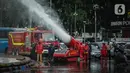 Petugas pemadam kebakaran menyemprotkan cairan disinfektan menggunakan robot LUF 60 di kawasan Bundaran HI, Jakarta, Minggu (22/3/2020). Pemprov DKI Jakarta melakukan penyemprotan fasilitas umum untuk mencegah penyebaran virus corona COVID-19. (Liputan6.com/Faizal Fanani)