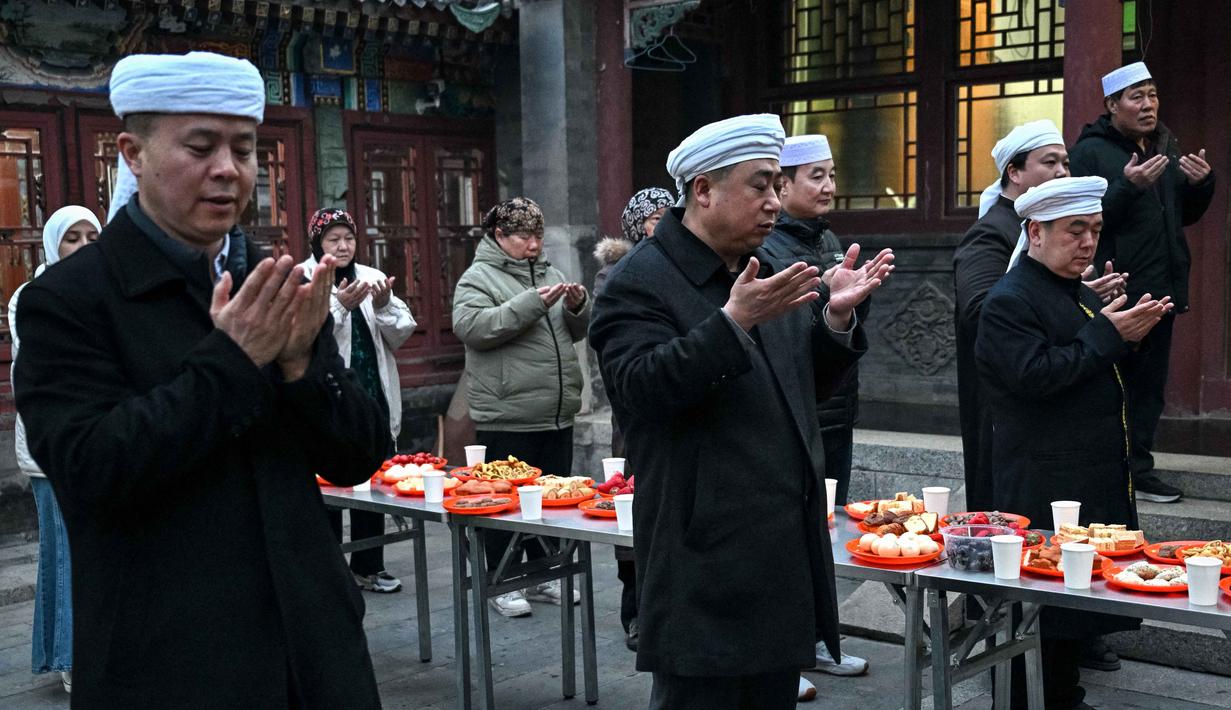 Di kota-kota dengan populasi Hui yang besar, seperti Linxia, suasana Ramadan terasa sangat kental dengan aktivitas berbagi sahur dan buka puasa bersama. Tampak dalam foto, warga Muslim etnis Hui Tiongkok membaca doa sebelum berbuka puasa di sebuah masjid selama minggu terakhir bulan suci Ramadhan di Beijing pada 17 Maret 2026. (Adek BERRY/AFP)