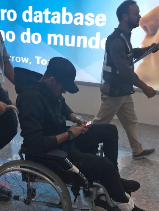 Pemain Paris Saint-Germain (PSG), Neymar menggunakan kursi roda setibanya di bandara Rio de Janeiro, Brasil, Kamis (1/3). Dokter mengatakan Neymar akan butuh waktu dua setengah sampai tiga bulan untuk bisa sembuh total (Claire Dornald Clauzel/Twitter/AFP)