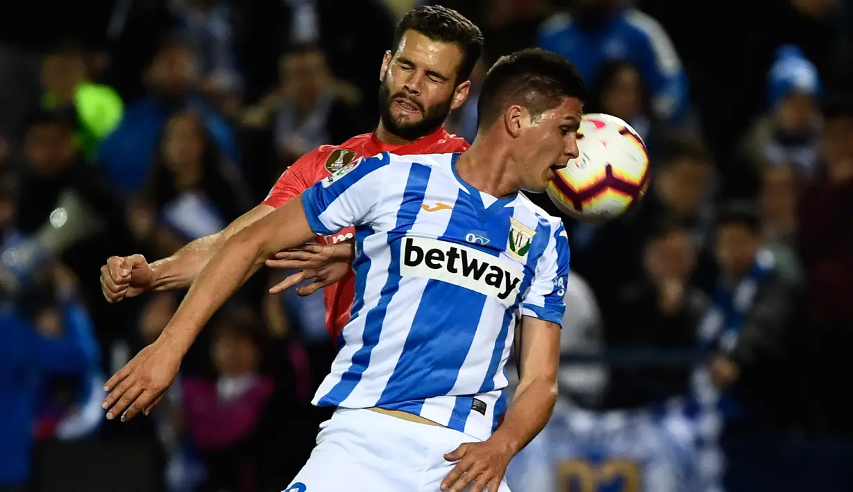 Pemain Leganes, Guido Carrillo berebut bola dengan bek Real Madrid, Nacho Fernandez dalam lanjutan La Liga 2018-2019 di Estadio Municipal Butarque, Senin (15/4). Real Madrid hanya mampu meraih hasil imbang 1-1 saat bertandang ke markas Leganes. (PIERRE-PHILIPPE MARCOU / AFP)