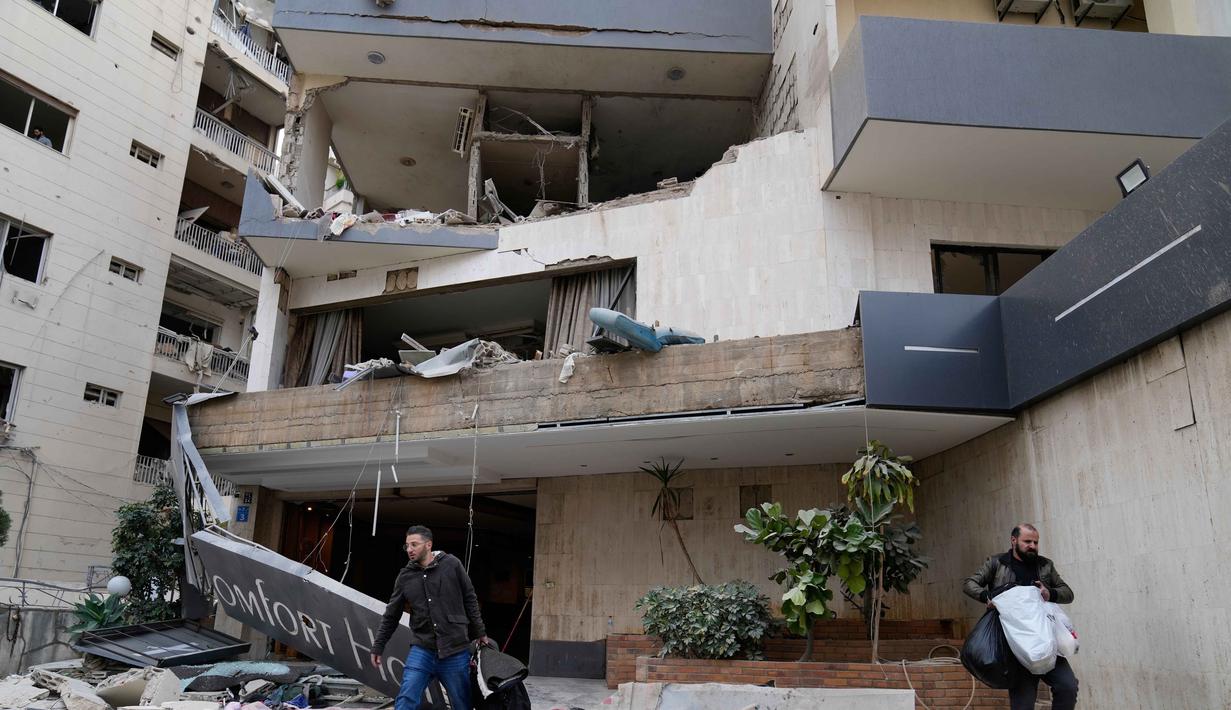 Israel menyebut serangan tersebut menargetkan fasilitas komunikasi satelit dan gudang senjata milik intelijen Hizbullah. Tampak dalam foto, para tamu hotel membawa barang-barang mereka saat meninggalkan hotel yang rusak akibat serangan udara Israel di Hazmieh, sebelah timur Beirut, Lebanon, Rabu 4 Maret 2026. (AP Photo/Hussein Malla)