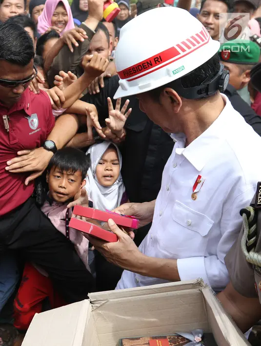 Presiden Joko Widodo atau Jokowi membagikan buku dan kain batik kepada warga yang tinggal di sekitar Bandara Soetta, Tangerang, Banten, Kamis (21/6). Bagi-bagi buku tersebut merupakan rutinitas Jokowi usai blusukan. (Liputan6.com/Angga Yuniar)