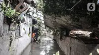Warga membersihkan sampah di rumahnya yang rusak akibat derasnya arus banjir di kawasan Kemang Timur XI, Jakarta Selatan, Minggu (21/2/2021). Longsor terjadi akibat derasnya arus kali yang kemudian bangunan menimpa permukiman warga di bawahnya. (merdeka.com/Iqbal S. Nugroho)