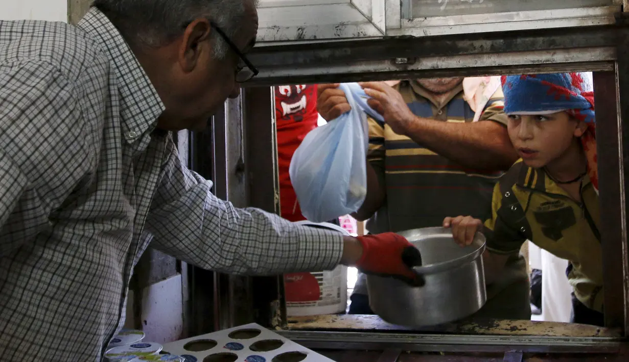 Seorang anak (kanan) saat menerima makanan buka puasa gratis yang didistribusikan bagi yang membutuhkan selama bulan puasa di masjid Abdul Qadir al-Gailani, Baghdad, Rabu (24/6/2015). (REUTERS/Khalid al-Mousily)