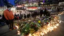 Seorang pria melihat lilin dan bunga yang diletakkan di lokasi terjadinya serangan truk di Stockholm, Swedia, Minggu (9/4). Sebuah truk yang dibajak menabrakkan diri ke kerumunan pejalan kaki pada Sabtu (8/4). (AP Photo / Markus Schreiber)