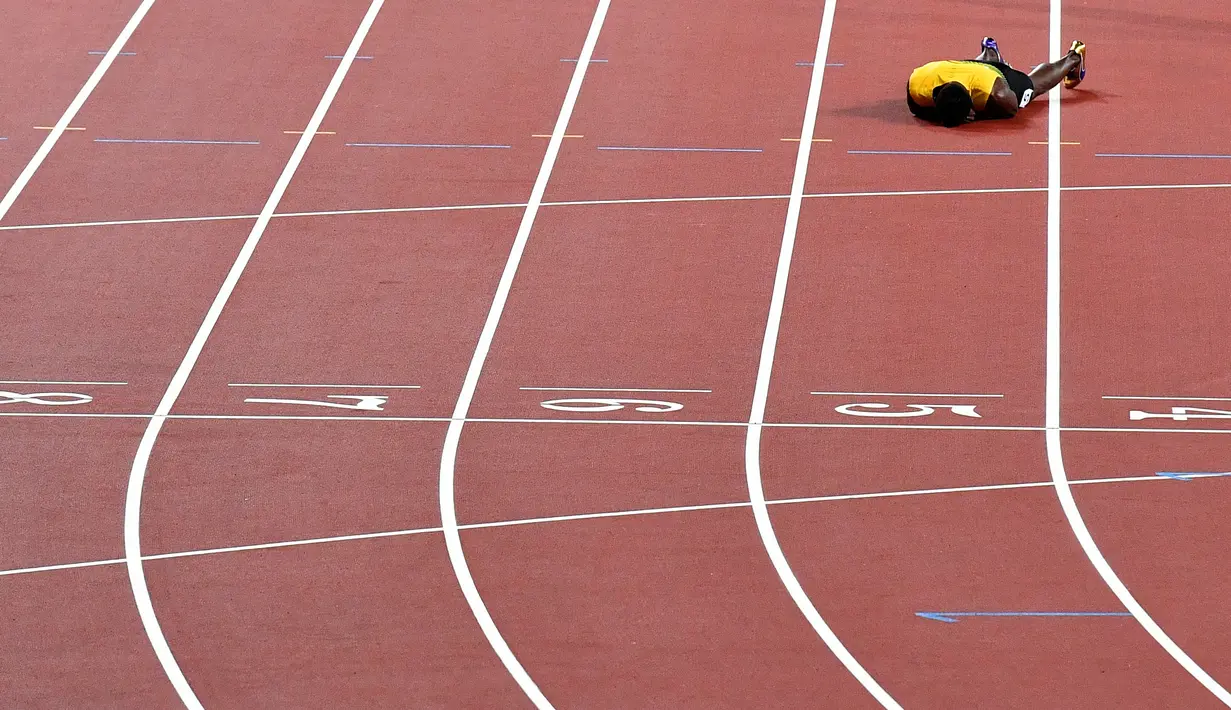 Pelari Jamaika, Usain Bolt terkapar di lintasan setelah terjatuh karena cedera di final 4x100 meter pada Kejuaraan Dunia Atletik di London, Sabtu (12/8). Bolt sempat tertatih-tatih sebelum akhirnya jatuh dan gagal melanjutkan lomba. (AP/Martin Meissner)