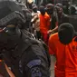 Polisi bersenjata lengkap mengawal sejumlah terduga teroris untuk dihadirkan dalam jumpa pers di Mabes Polri, Jakarta, Jumat (17/5/2019). Sepanjang bulan Mei 2019, tim Densus 88 Antiteror telah menangkap sebanyak 29 terduga teroris jaringan Jamaah Ansharut Daulah (JAD). (Liputan6.com/Johan Tallo)