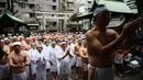 Orang-orang percaya Shinto dari Kuil Teppozu Inari berdoa sebelum mandi dengan air dingin untuk memurnikan jiwa dan tubuh mereka selama ritual Tahun Baru di Tokyo (12/1/2020). Sekitar 100 orang percaya Shinto ambil bagian dalam ritual tahunan tersebut. (AFP/Charly Triballeau)