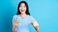 Seorang perempuan menggunakan aplikasi dompet digital di ponselnya.